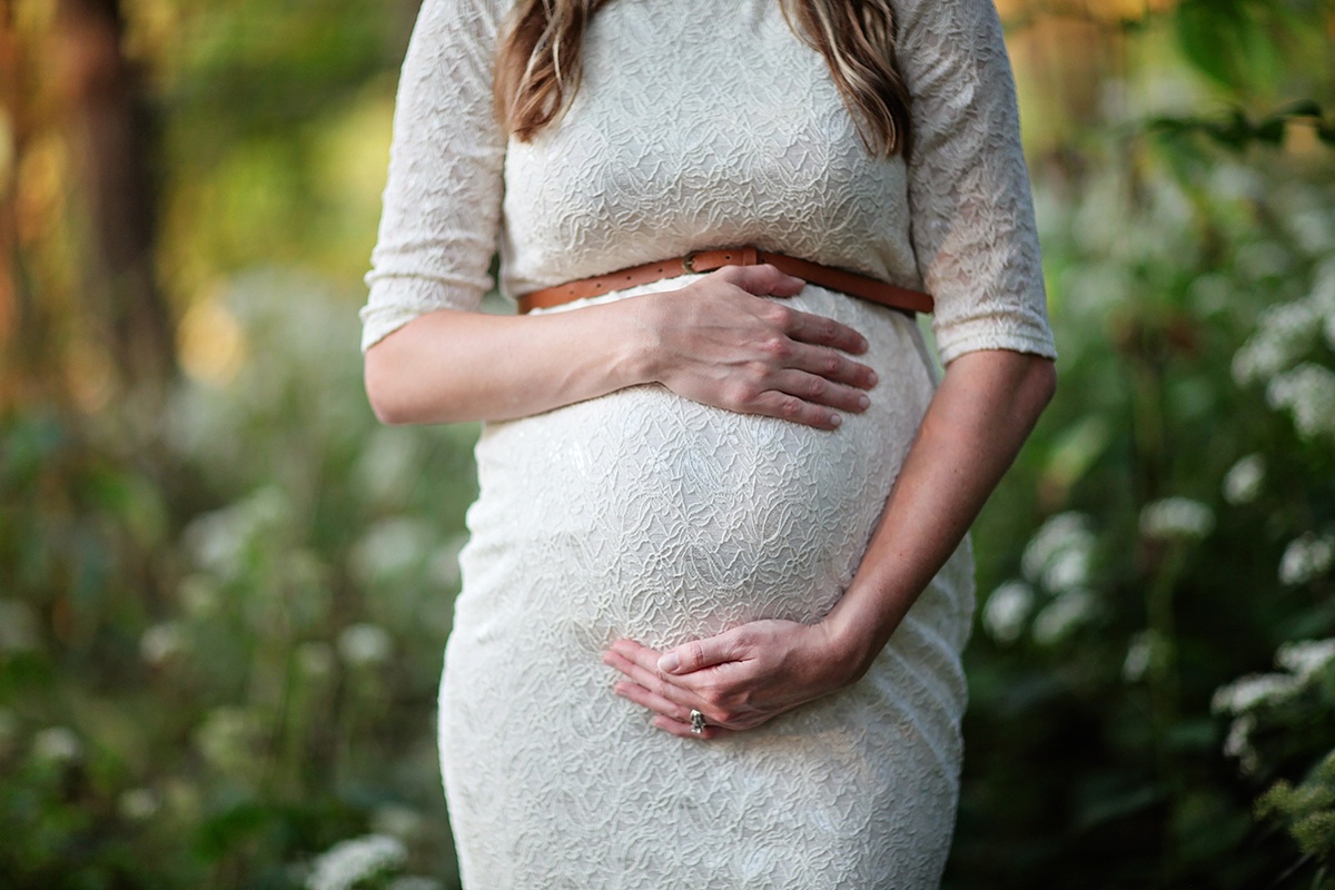 Eine schwangere Frau hält ihren Bauch.