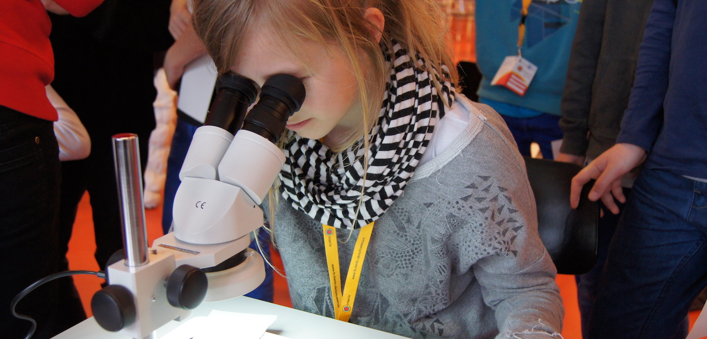 Mädchen schaut durch Mikroskop