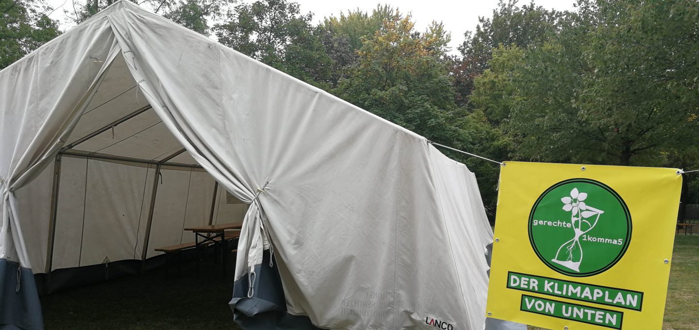 Zelt auf dem We4FutureCamp. Daneben ein gelbes Plakat mit Sanduhr und Klimaplan von unten